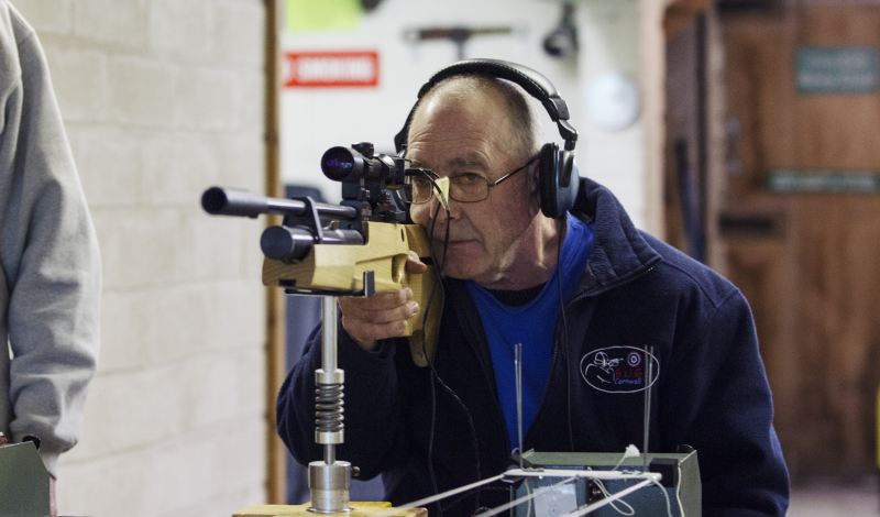 A member of the Blind Using Guided Sights club aiming his rifle towards an audible target.