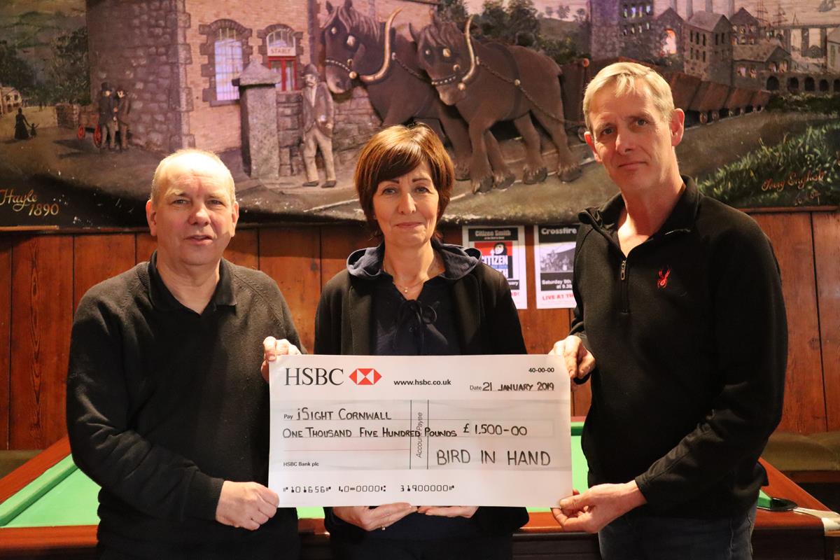 Carole from iSightCornwall along with two staff members from the 'Bird in Hand' pub holding a large cheque for £1500.