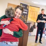 iSightCornwall Chief Executive, Carole hugs a volunteer as they are presented with an award at the recent AGM. Colonel Bolitho OBE stands in his uniform in the background.
