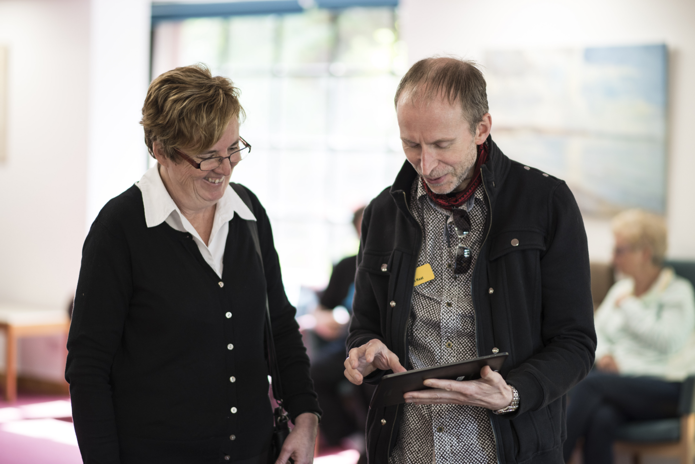 iSightCornwall Assistive Technology Officer, Rodney Keats speak with a client at a sight loss awareness event. Rod is holding a tablet computer.