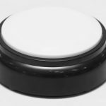 A white button on a black base, in the shape of a hockey puck.
