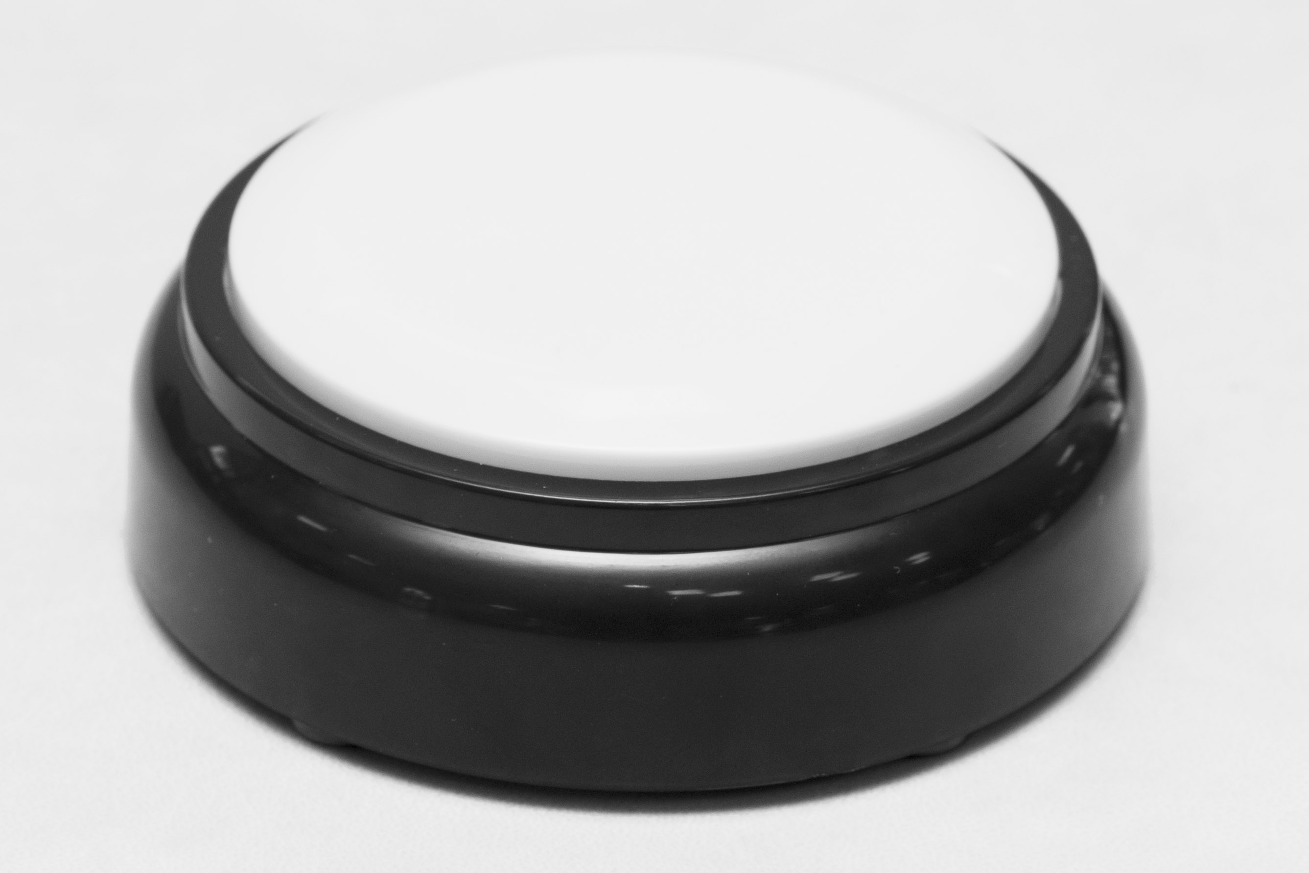 A white button on a black base, in the shape of a hockey puck.
