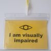 A yellow rectangle badge with the words I am visually impaired sits in a clear plastic wallet