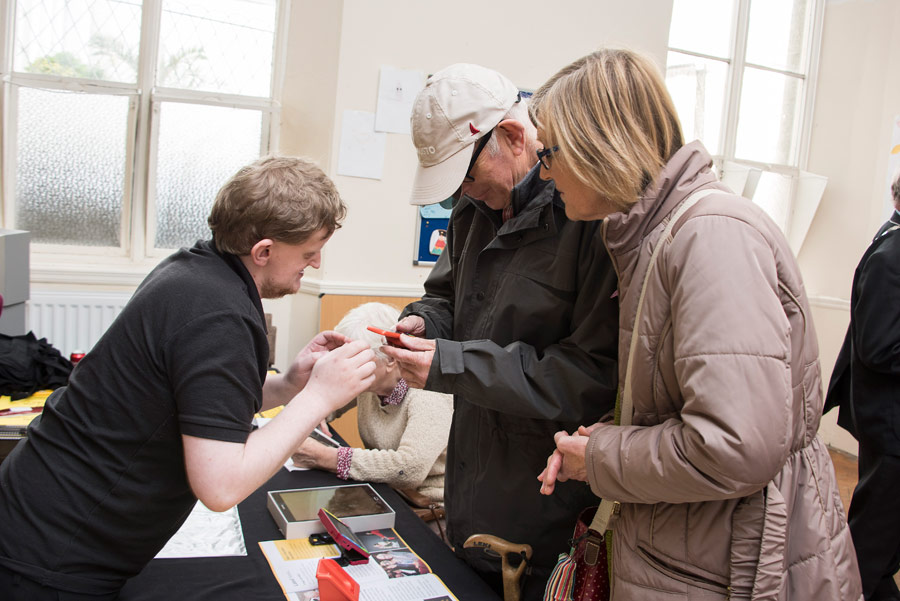 Image shows a staff member assisting people at a recent Sight Loss Awareness Day