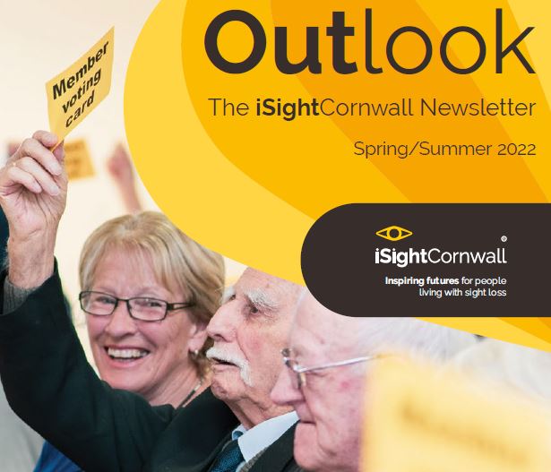 The cover for Outlook Spring 2022 featuring a man holding up is yellow voting card in the iSightCornwall AGM and a woman smiling at him