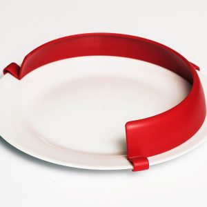 A bright red plate guard attached to a white plate.