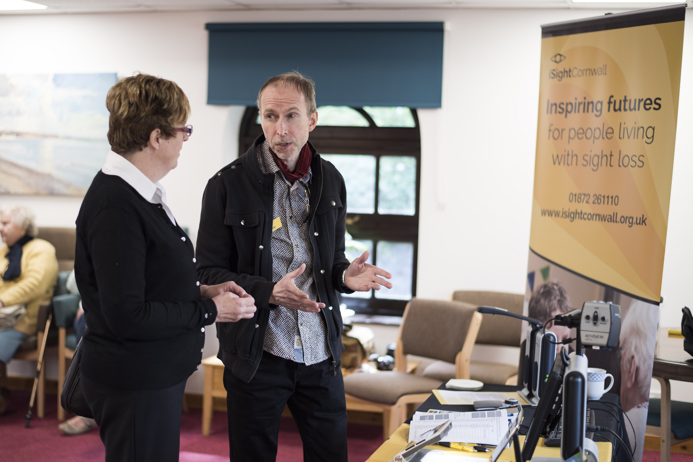 iSightCornwall Assistive Technology Officer, Rodney Keats speak with a client at a sight loss awareness event.