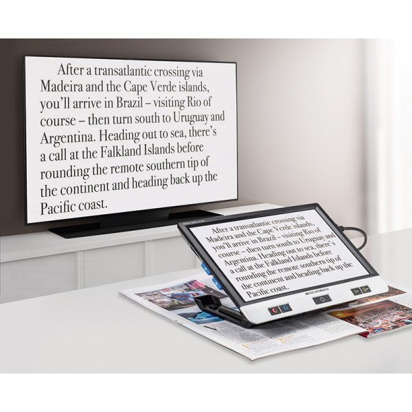 The Vixolux Digital XL FHD magnifier connected to a large flat screen television displaying magnified text from a magazine.