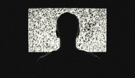 A man in a dark room watching television