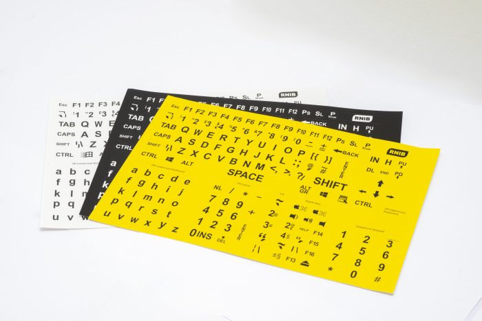Sheets of keyboard stickers in different contrasts. The top has black writing on yellow, the next white writing on black background and the last has black writing on white.