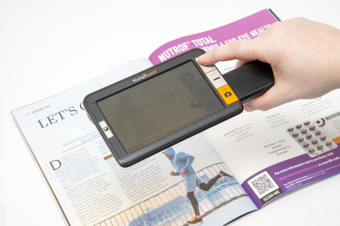 An electronic magnifier is held over a magazine